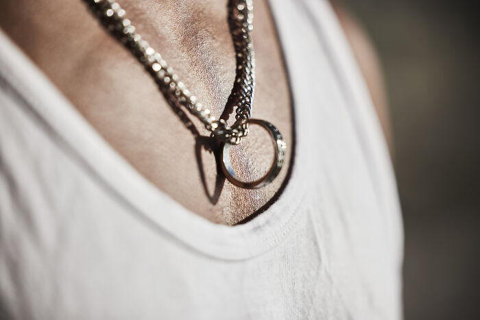 Close-up of a person wearing a ring necklace, highlighting an unexplainable creepy vibe through detailed texture and lighting.