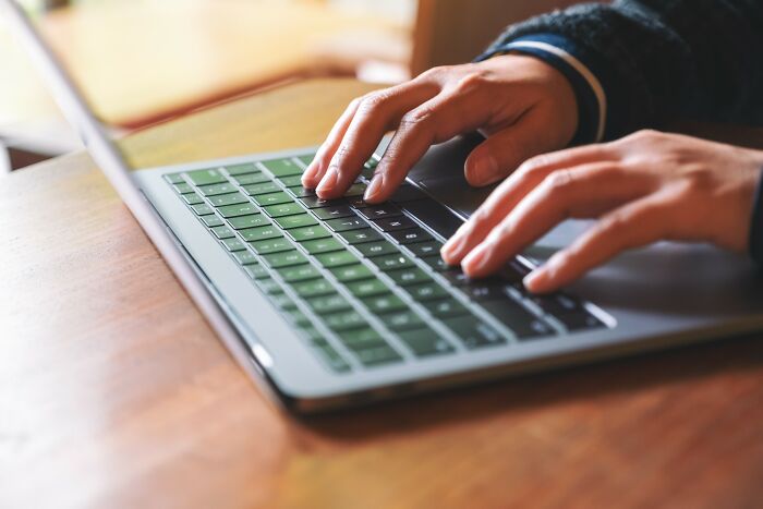 Person typing on laptop keyboard with focus on hands representing simple car stuff skills learning online.