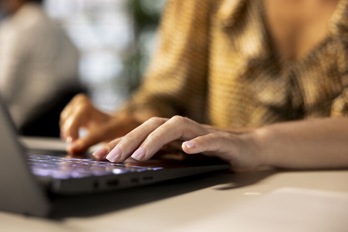 A woman in a patterned blouse typing on a laptop keyboard, related to boss wife claim and innocent worker.