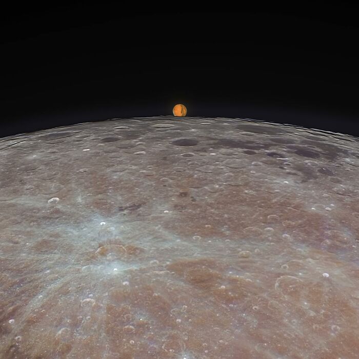 Close-up astronomy photo of the moon's surface with a rising celestial body showing the beauty and mystery of space.