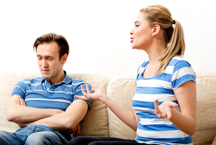 Wife expressing frustration to husband on couch, highlighting challenges of cleaning bed repeatedly without his cooperation.