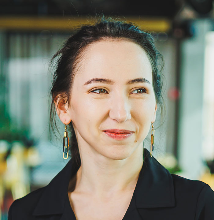 Young woman in a professional setting, smiling thoughtfully, illustrating experiences of blatant work nepotism recalled by employees.