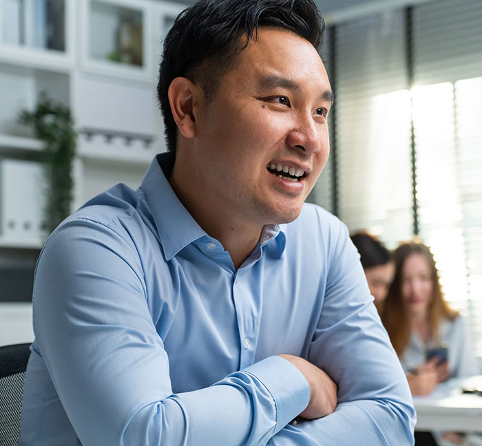 Smiling man in blue shirt in office setting, representing work nepotism in a professional environment conversation.