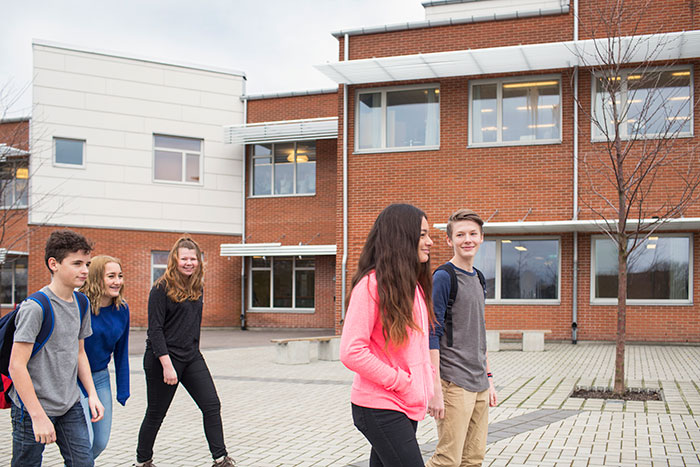 Group of young people walking outside a building, illustrating social dynamics related to work nepotism cases witnessed.