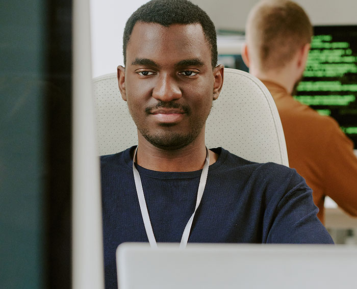 Young man working at computer in office, representing workplace environment and work nepotism discussions.