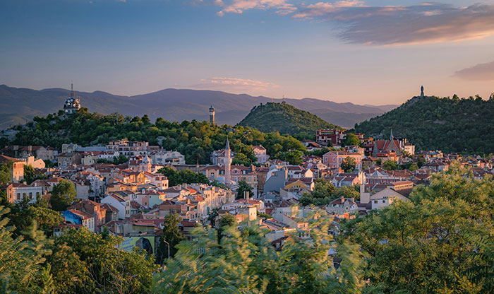 Panoramic view of a city at sunset surrounded by hills, illustrating spooky urban legends from cities around the world.