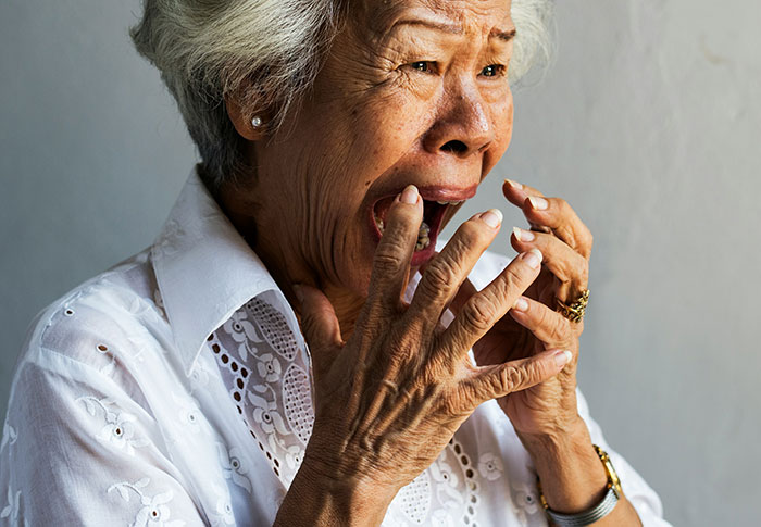 Elderly woman expressing shock and fear while reacting to creepy found footage and videos on a neutral background.