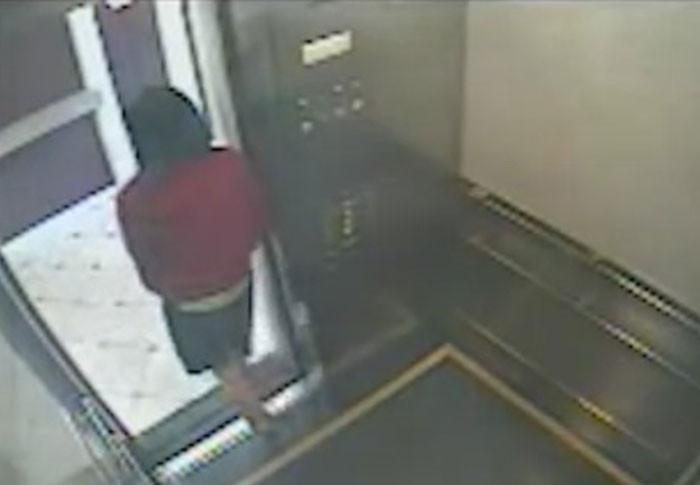 Person in a red jacket stepping into an elevator captured on creepy found footage security video.