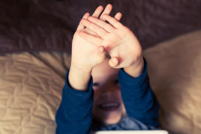 Child in a dark room raising hands with blurred face, evoking a creepy thing home stories atmosphere.