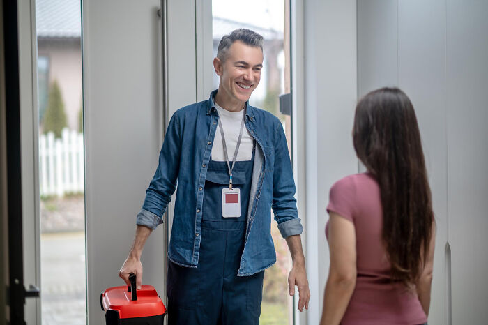 Technician smiling while entering a home with toolbox, relating to creepy thing home stories and service visits.