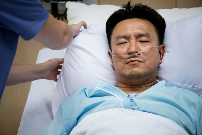 Man lying in hospital bed with oxygen tube, appearing distressed, illustrating chaotic breakup stories keyword concept.