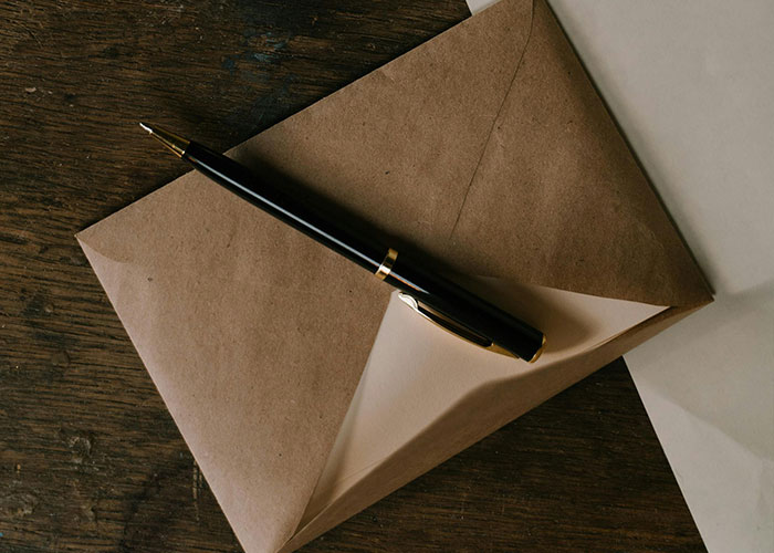 Envelope with a black pen on a wooden surface symbolizing a teen torn about continuing to see biological mom. Envelope with a black pen on a wooden surface symbolizing a teen torn about continuing to see biological mom.