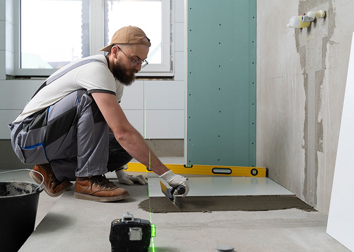 Man installing tiles on floor in daughter&rsquo;s home renovation with dad upset about the unusual changes and worries expressed