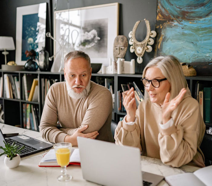 Older parents discussing plans on a laptop, illustrating parents kick out daughter for moving into her remodeled room.