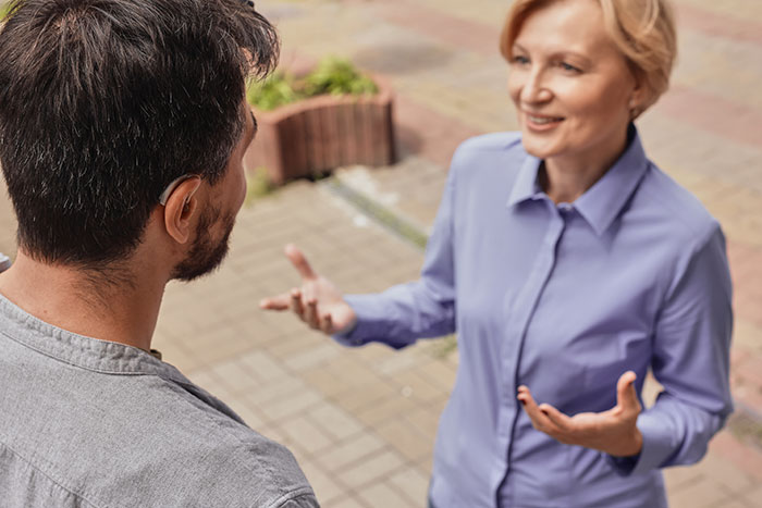 Two people having a serious conversation outdoors, illustrating sibling refuses to keep paying rent to parents after discovery.