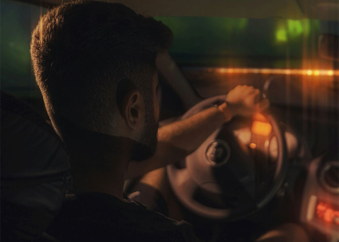 Man with short hair driving a car at night, representing a villain in someone's story theme.