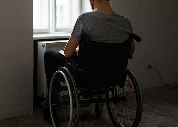 Person in a wheelchair facing a window in a dim room, illustrating the theme of being a villain in someone else’s story.