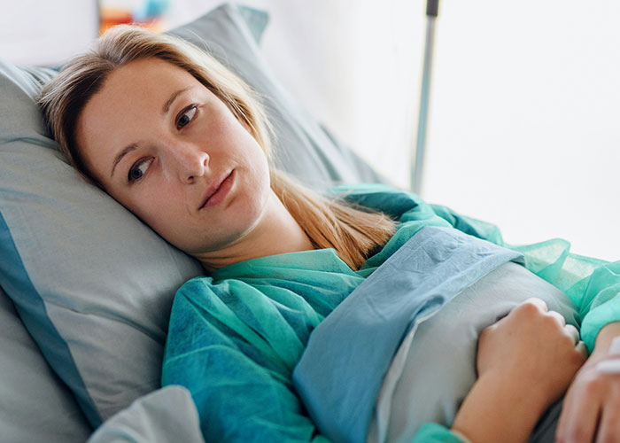 A woman lying in hospital bed looking thoughtful, reflecting the theme of villain in someone else’s story.