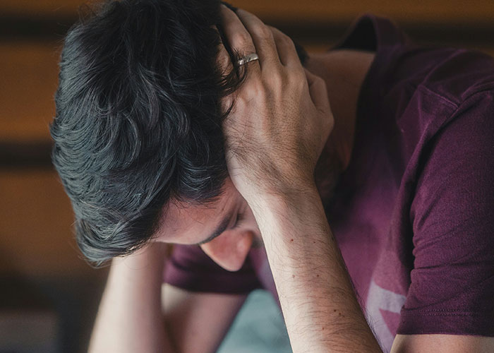 Man holding his head in frustration, illustrating emotional impact of being a villain in someone else’s story.
