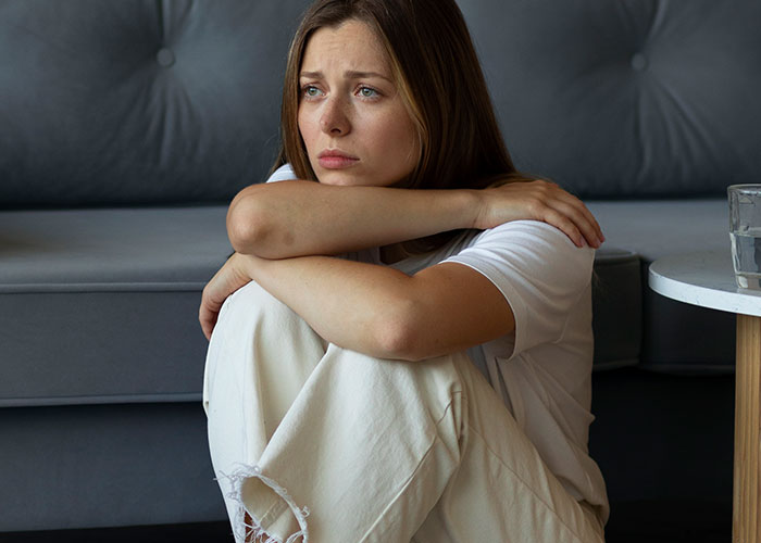 Sad woman sitting on the floor with arms wrapped around knees, reflecting on being the villain in someone else’s story.