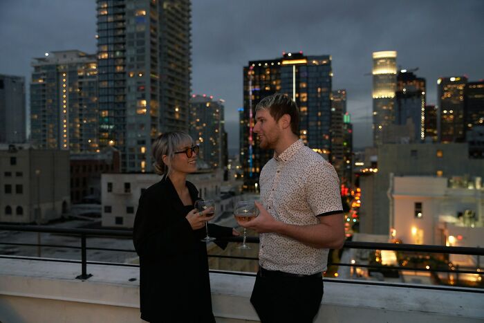 Two people having a drink on a rooftop at night.