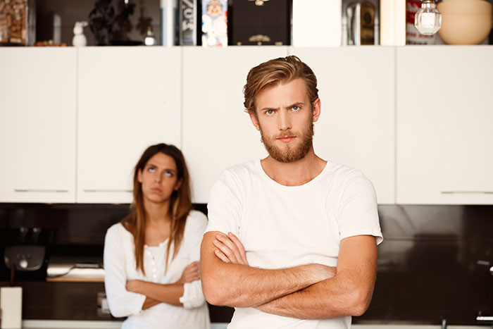 Young man refusing to care for disabled brother, parents begging, sister upset, tense family conflict in modern kitchen.