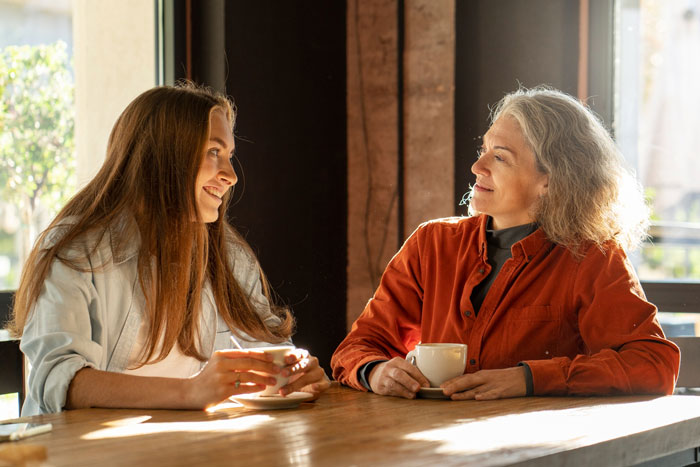 Woman and stepdaughter having a heartfelt conversation over coffee, reflecting on the bonus mom and mom roles.