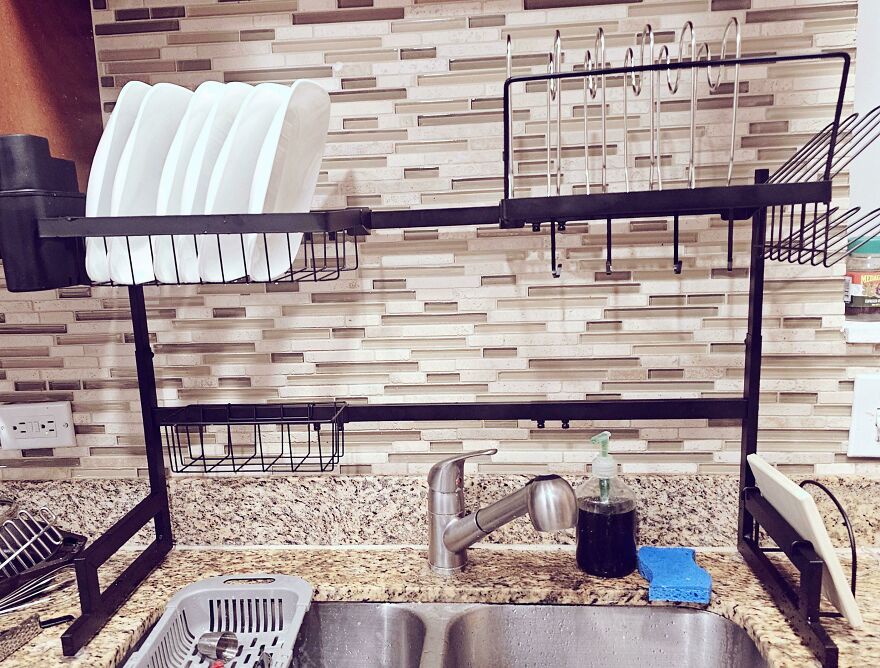 Kitchen dish drying rack with organized plates and utensils above sink, demonstrating effective organization hacks at home.