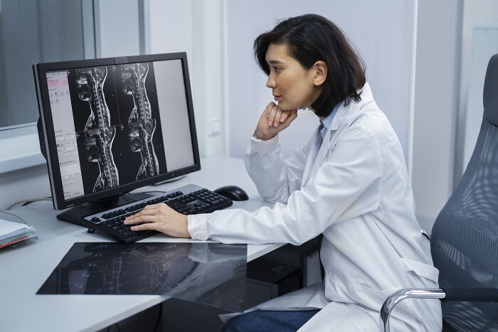 Doctor examining spine MRI scans on a computer, reflecting on challenging first opinions in a medical setting.