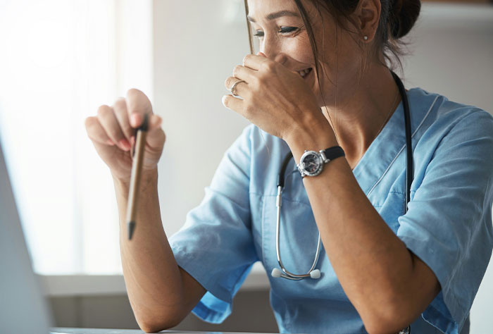 Female doctor smiling while working on a laptop, illustrating times Google was wrong or accurate in diagnosing people.