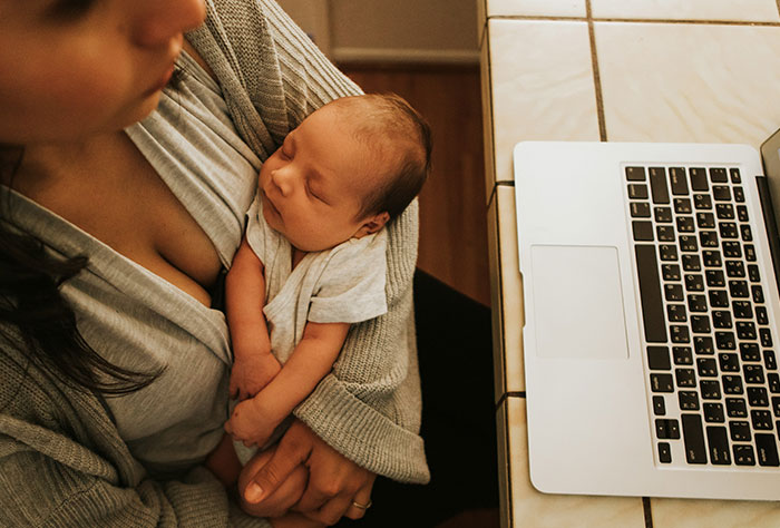Woman holding newborn baby near laptop, illustrating moments when Google was accurate or wrong in diagnosing people.