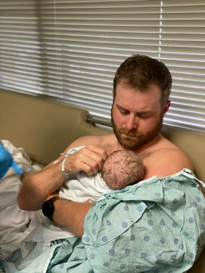 Father holding newborn baby on hospital bed, capturing one of the craziest and funniest things that happened during birth.