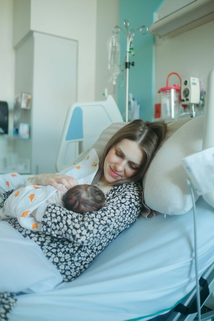 Mother holding newborn baby in hospital bed, capturing craziest and funniest moments that happened during birth.