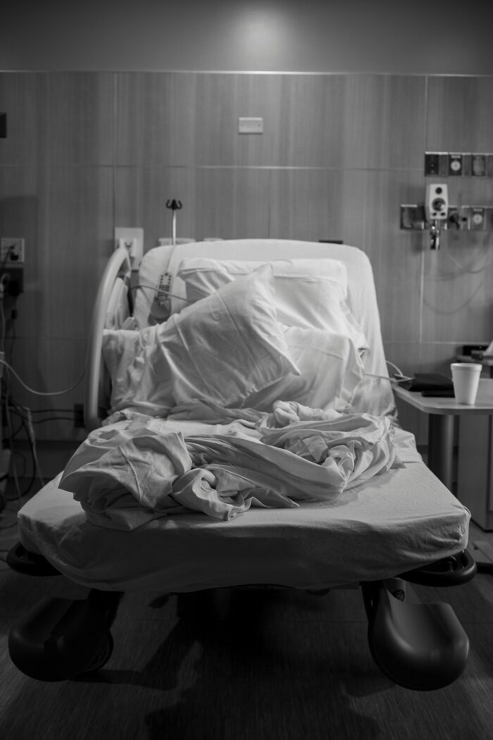 Hospital bed with messy sheets and pillows in a dimly lit room, capturing craziest and funniest moments during birth.