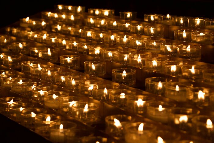 Rows of small candles burning softly in a dark setting, creating a warm and calm atmosphere related to birth moments.