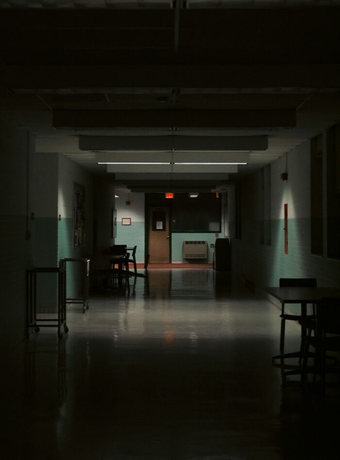 Dimly lit hospital hallway with empty chairs and tables, evoking the creepy experiences hospital workers have shared.