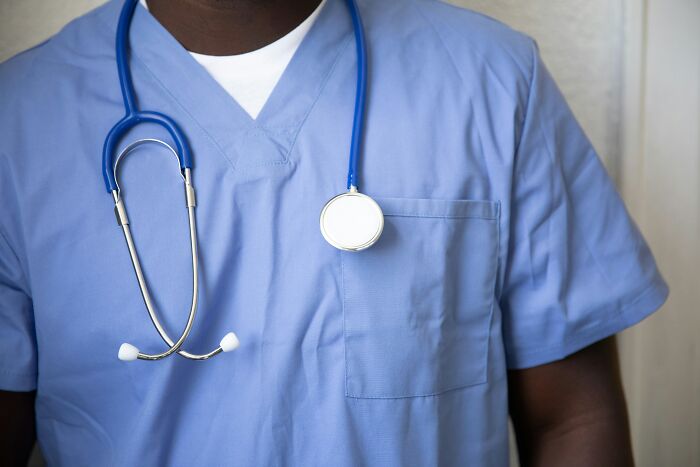 Hospital worker wearing blue scrubs and a stethoscope, representing creepy experiences shared by hospital workers.