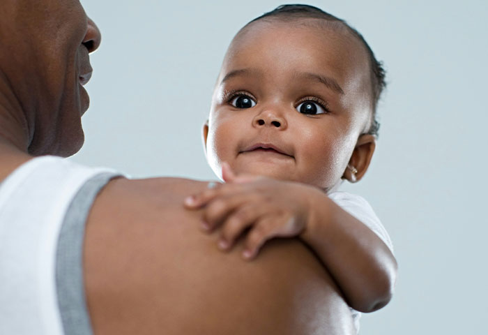 Baby with wide eyes being held by adult, related to doctors witnessing birth meltdowns and cheating incidents.