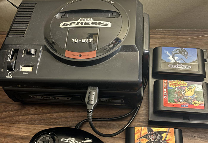 Sega Genesis 16-bit console and game cartridges on wooden surface, highlighting classic gaming and nostalgic entertainment.