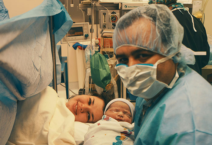 Sala de parto con recién nacido y personal médico en ambiente que refleja caos tras descubrir infidelidad.