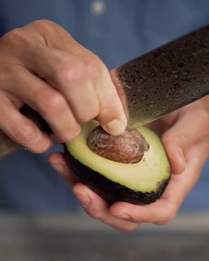 Close-up of hands cutting avocado with a knife, illustrating the common mistake linked to avocado hands injuries.