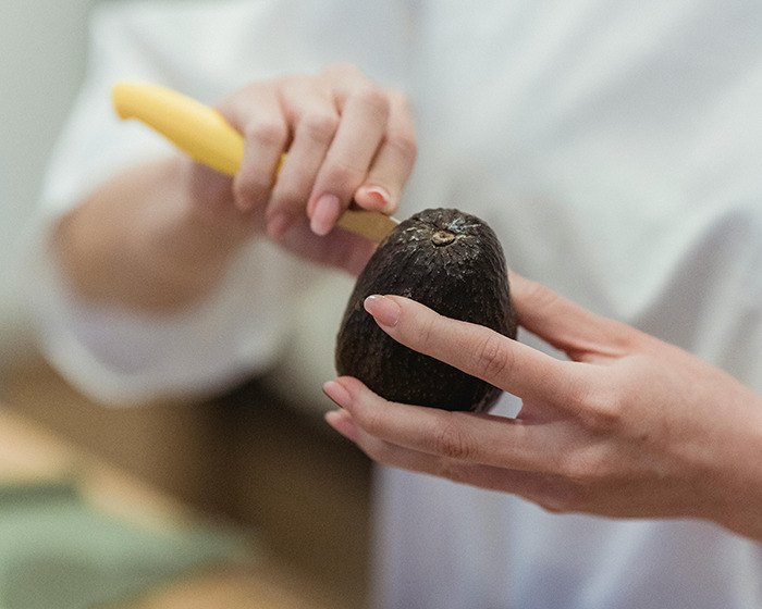 Person holding avocado and knife, demonstrating common mistake linked to doctor's avocado hands warning and ER visits.