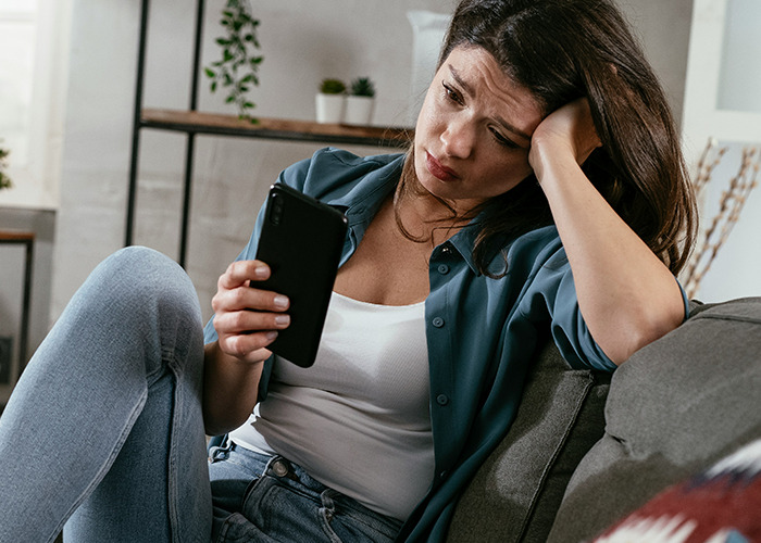 Woman looking concerned while using a smartphone, reflecting on the real benefits of marriage for women.