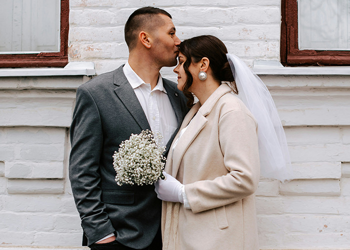 Newlywed couple in wedding attire sharing a tender moment outdoors, symbolizing benefits of women getting married.