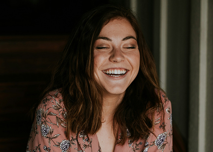 Smiling woman with brown hair wearing a floral blouse, discussing benefits of marriage for women in a casual setting.