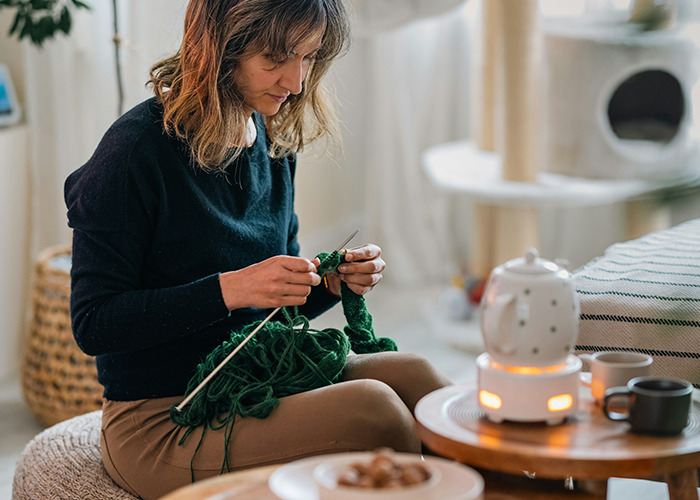 Woman knitting at home, reflecting on the real benefits of marriage for women with thoughtful expression