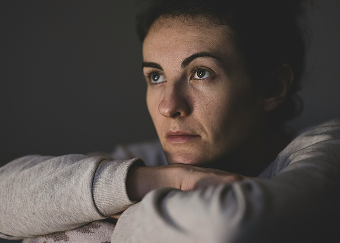 Woman with a contemplative expression resting her arms, reflecting on the benefits of marriage for women.