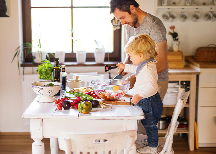 Man and child cooking together in a bright kitchen, illustrating family life benefits for women in marriage discussions.