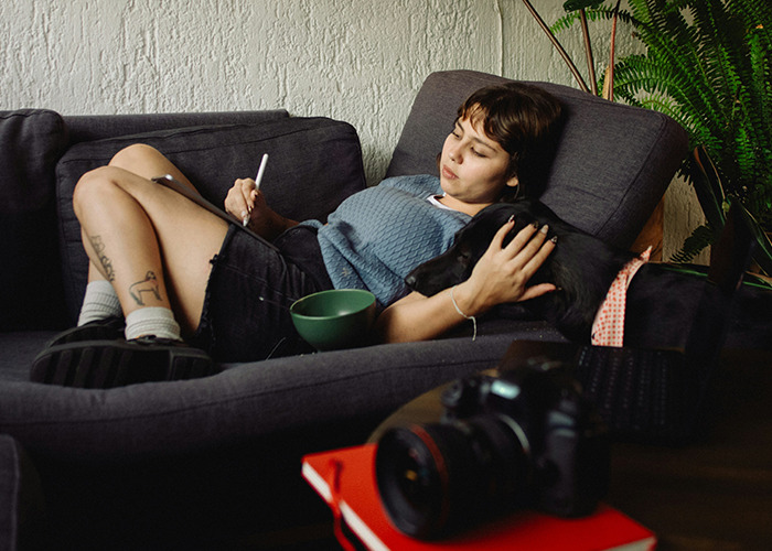 Woman relaxing on a couch with a dog, writing in a notebook, exploring benefits of marriage for women.