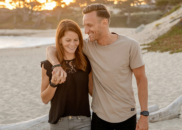 Couple walking on beach holding hands smiling, illustrating benefits of marriage for women and relationships.